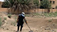 Activité de déminage devant une école de la ville de Deir-ez-Zor Homme en tenue de démineur scanne une zone devant une école