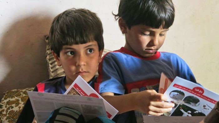 Im Irak schauen zwei Brüder Prospekte an, die das Team von Handicap International am Ende einer Sitzung abgegeben hat Im Irak schauen zwei Brüder Prospekte an, die das Team von Handicap International am Ende einer Sitzung abgegeben hat